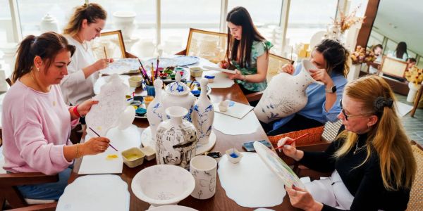 A group painting and decorating ceramic vases and plates.