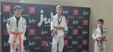 Podium de judo avec trois jeunes compétiteurs.