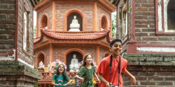 Children exploring an ancient temple with Buddhist statues.