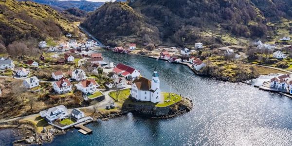 A scenic lakeside village with a white church on a small peninsula.