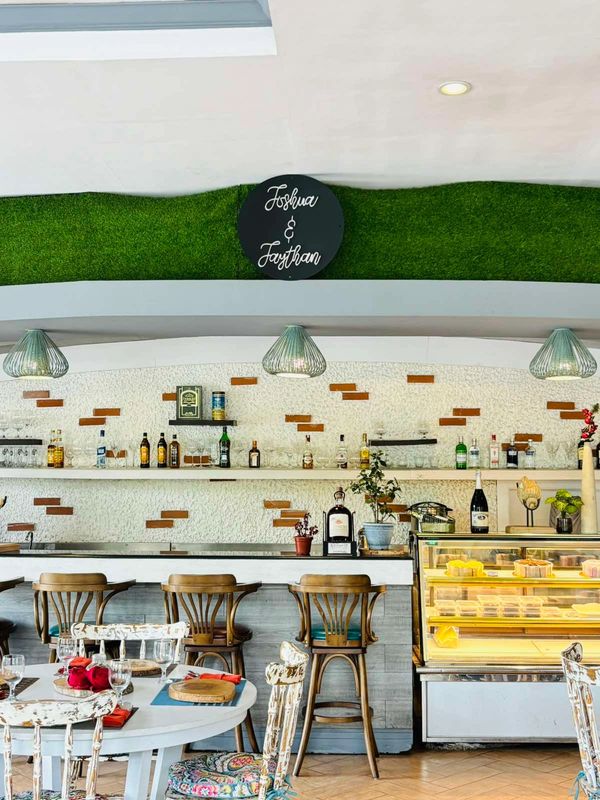 Cozy bar area with wooden stools and a display case of desserts.