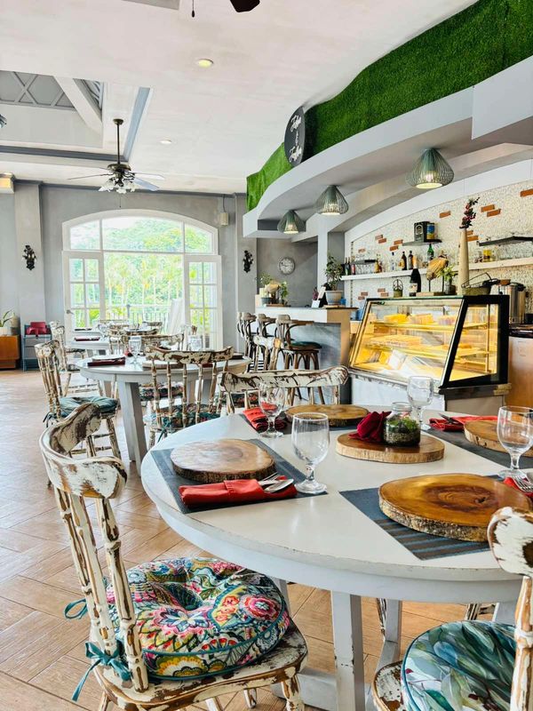 Bright, rustic cafe with wooden chairs and tables set for guests.