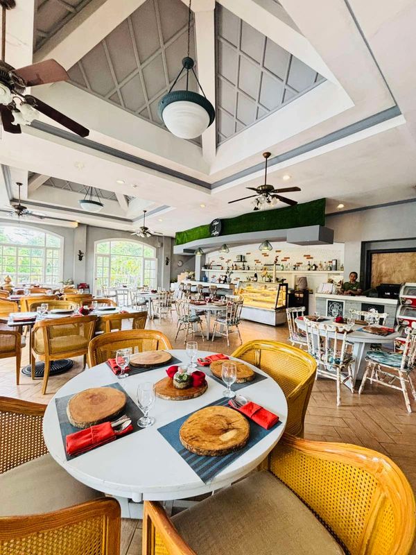 Bright and cozy restaurant interior with wooden chairs and elegant table settings.