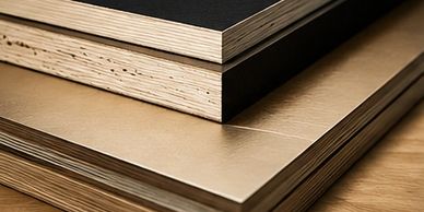 Stacked plywood sheets with different finishes on a wooden surface.