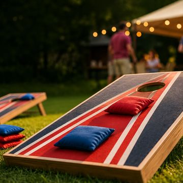 Outdoor cornhole game setup with bean bags on a lawn during evening.