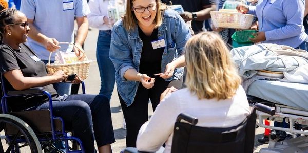 Community volunteers engaging with people in wheelchairs outside a church on a sunny day.