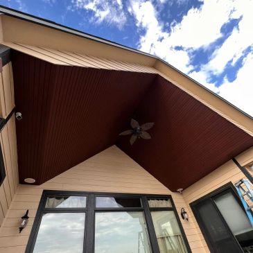 Modern house patio roof with a ceiling fan and blue sky.
