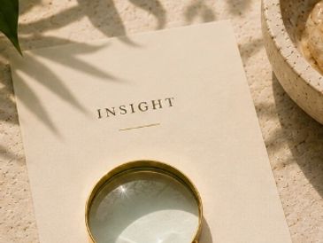 Magnifying glass on a card with the word 'INSIGHT' under soft natural light.