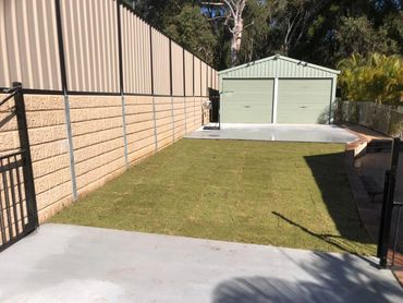 A neat backyard with a grassy area and a green double-door shed.