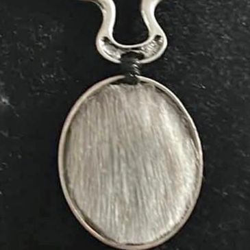 Close-up of a pendant with a brushed metal surface and a loop attachment.