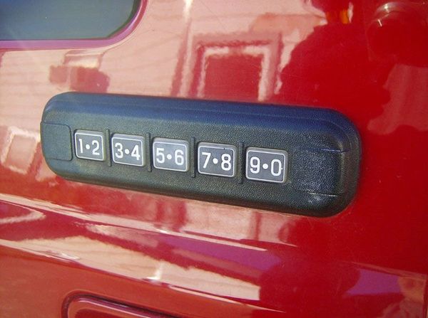 Keypad entry system on a red vehicle door for keyless access.