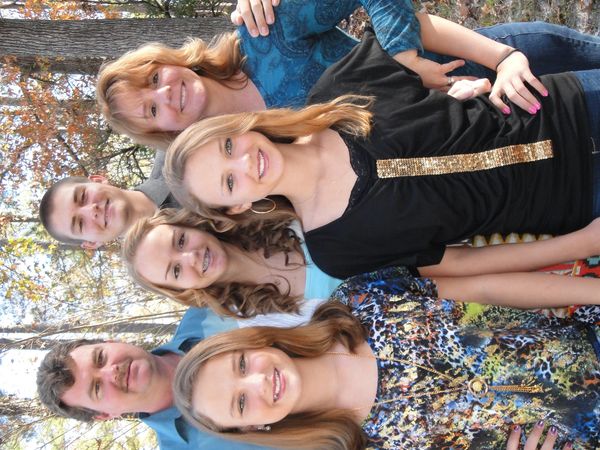A smiling family of six posing outdoors in autumn.