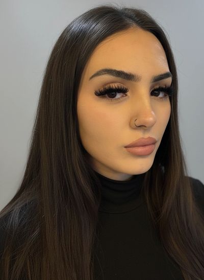 Portrait of a young woman with long dark hair and dramatic eyelashes.