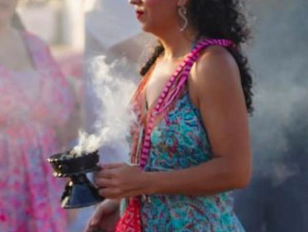Woman in colorful dress holding a smoking incense burner.
