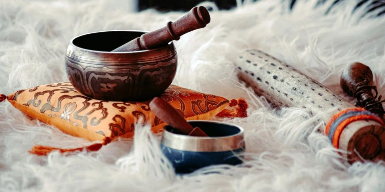 Tibetan singing bowls with mallets on a soft white fur surface.