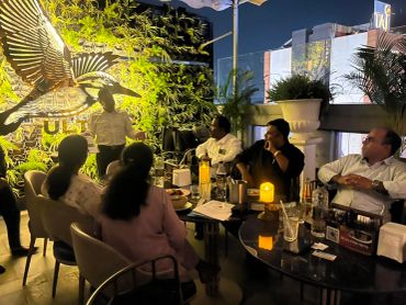 Group of people in a dimly lit outdoor meeting.