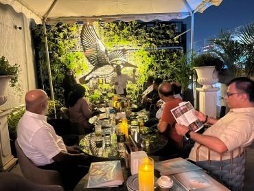 Group of people dining outdoors under a tent at night.