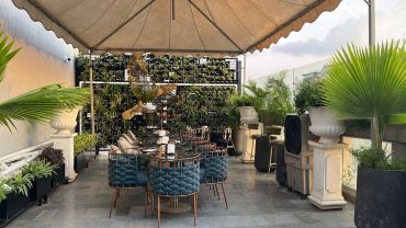 Outdoor patio dining area with plants and canopy.