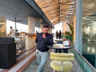 Man leaning on a table at an outdoor cafe.