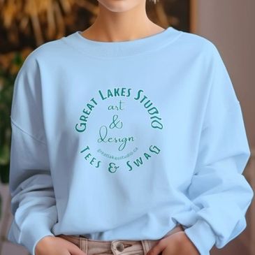 Woman wearing a light blue sweatshirt with Great Lakes Studio logo.