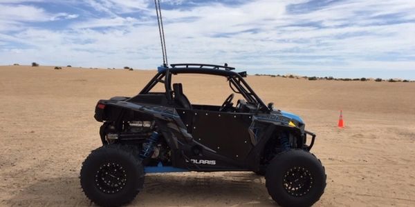 Black Polaris off-road vehicle on sandy terrain.