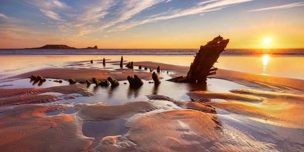 Helvetica Wreck on Rhossili Beach in the sunset, with Worms Head in the background