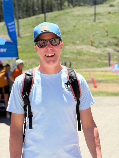 Man wearing sunglasses and a blue cap outdoors.