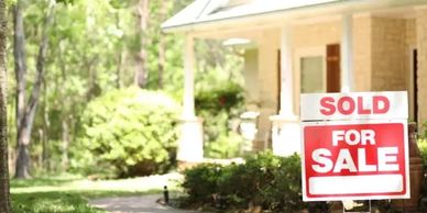 A house with a sold-for-sale sign in the front yard.