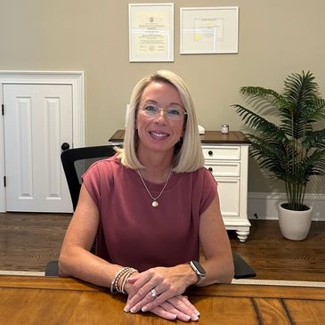 A professional woman sitting at a wooden desk in a well-decorated office.