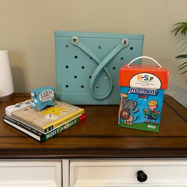 Speech therapy tools including books, sound cubes, and a treatment kit on a wooden table.