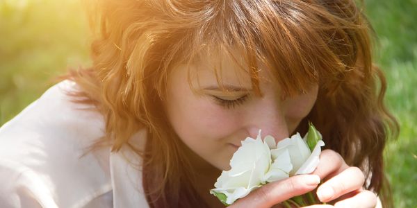Woman smelling white flowers outdoors.