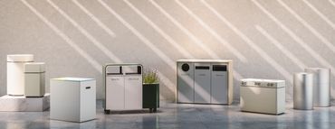 Various modern recycling bins lined up against a wall with striped shadows.