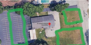Aerial view of a building with parking and grassy areas marked in green.