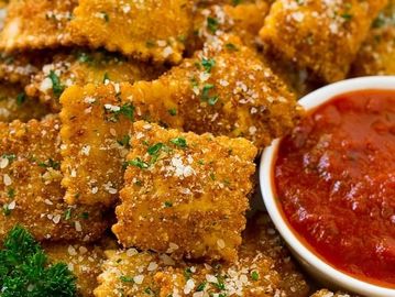 Crispy breaded ravioli with marinara sauce and parsley garnish.