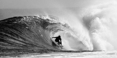 Surfer riding a large wave in black and white.