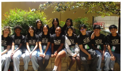 Group of young people posing outdoors with matching black shirts.