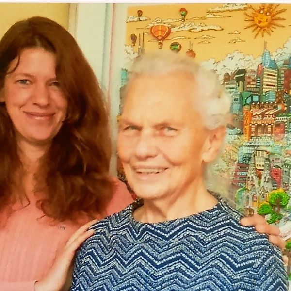 A smiling younger woman Frau Bieser and an elderly woman Frau Elwes posing together indoors.