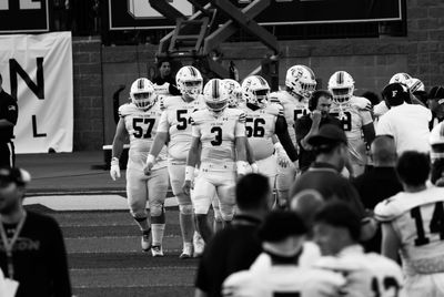 Football players walking on the field in black and white.