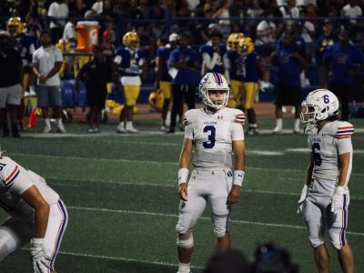 High school football players in white uniforms on the field.