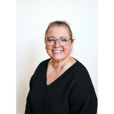 Smiling woman in glasses and black sweater against white background.