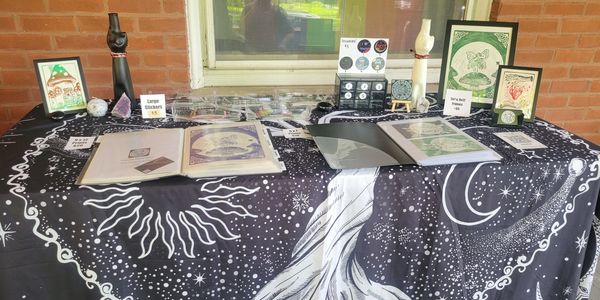 A celestial-themed table display with framed art, books, and merchandise.