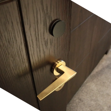 A dark walnut wooden door with a minimalist designed brass hotel door lock installed.