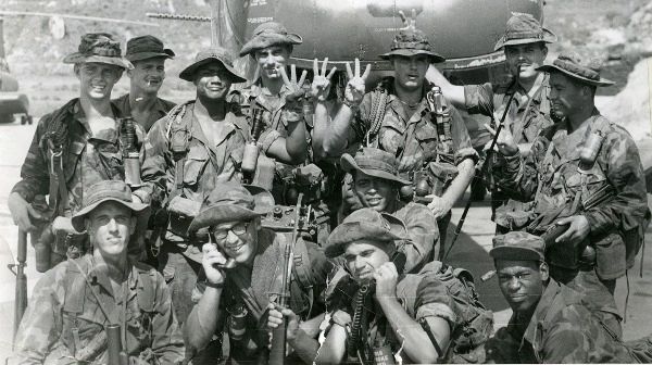 An old photograph of Vietnam soldiers posing in front of a helicopter. 