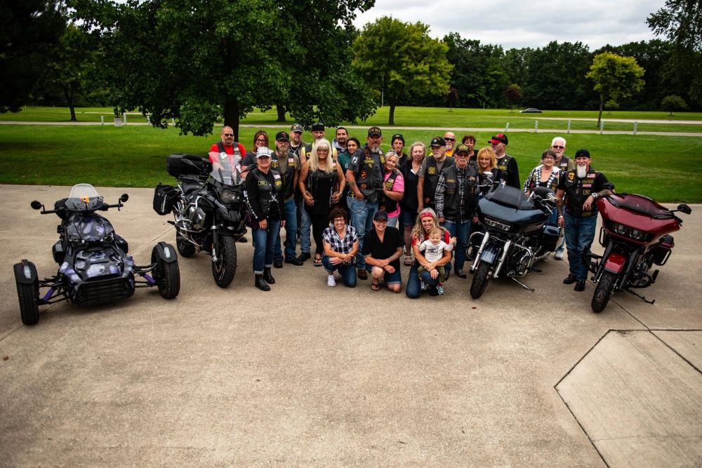 Members posing with their motorcycles in a park