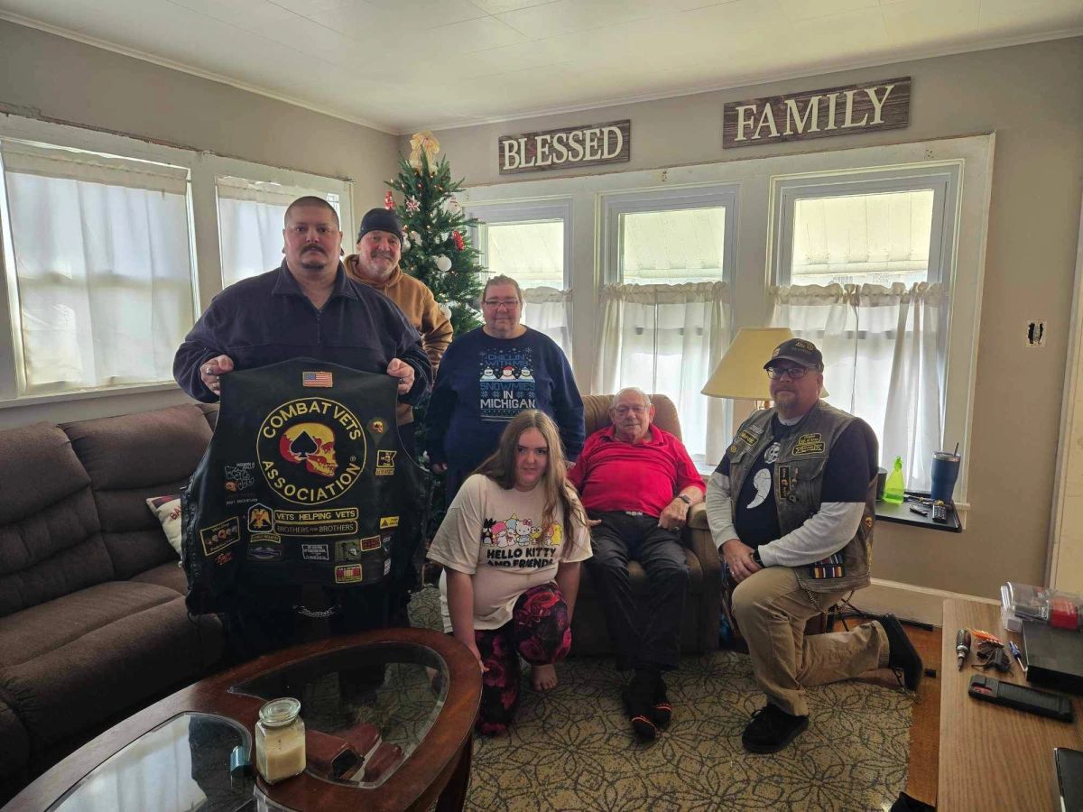 Chapter members and families posing with a Combat Veterans Association banner
