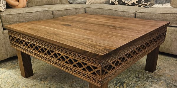 Square wooden coffee table with intricate carved design.