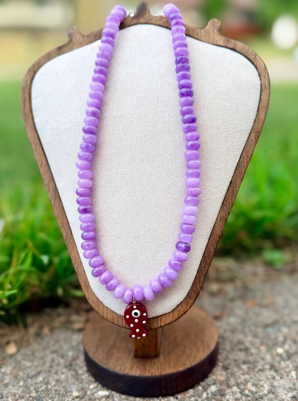 Lavender beaded necklace with a red fish pendant.