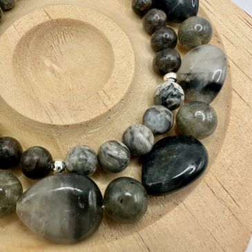 Black and grey beaded necklace on wooden holder.