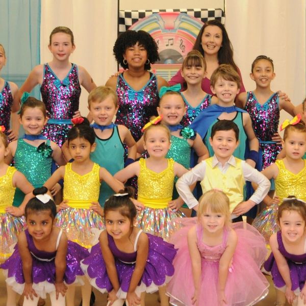 Group of kids in colorful dance costumes posing for a picture.