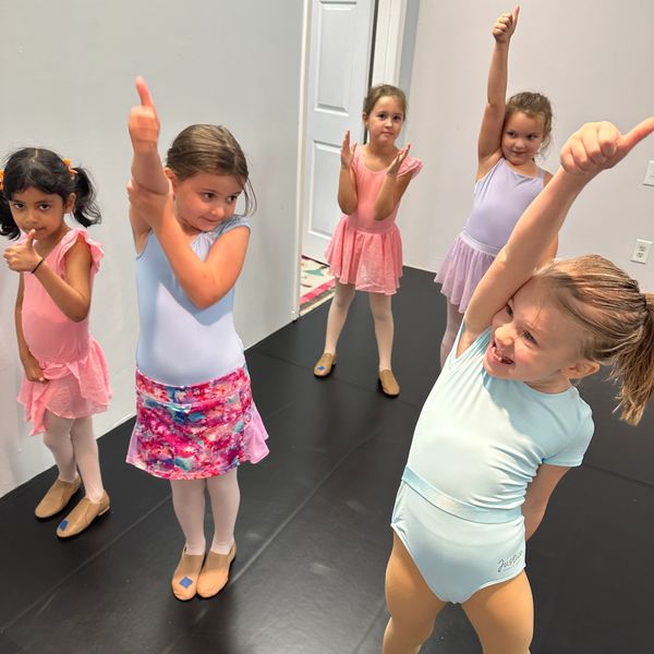 Five young girls practicing ballet in colorful outfits.